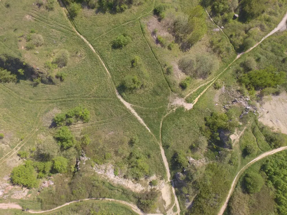 One of the drone photos, looking straight down at grass, paths and pale rock.