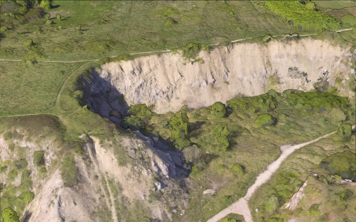 The quarry face in 3D, built entirely of coloured points: pale rock, green scrub and trees, a footpath.